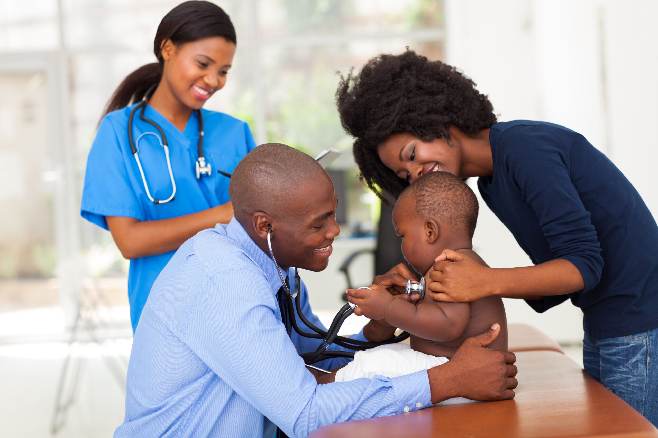 cheerful african mother and her son in doctor's office with male doctor and female nurse
